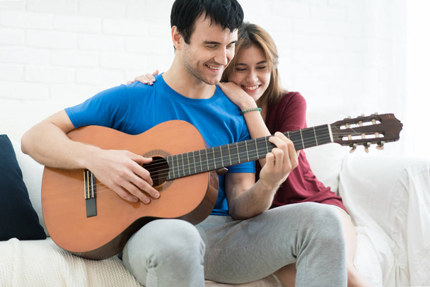 Lover couple young man resting at home and playing guitar for hi - Foto, imagen