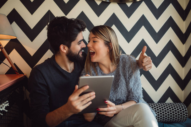 Pomocí tabletu v kavárně šťastný mladý pár. Jsou online, nakupování, čtení Skvělé zprávy. - Fotografie, Obrázek