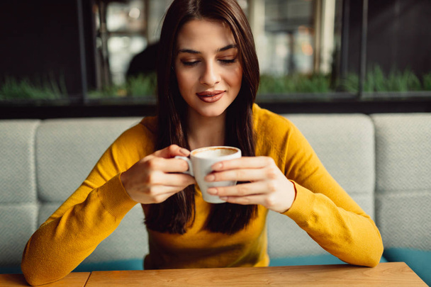 Zbliżenie piękna brunetka podczas picia kawy w kawiarni. - Zdjęcie, obraz