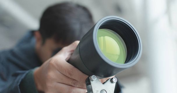 Человек смотрит через телескоп, чтобы наблюдать за местом обитания птиц
 - Фото, изображение