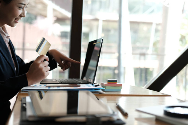 mulher segurando um cartão de crédito e usando computador para shoppi on-line
 - Foto, Imagem
