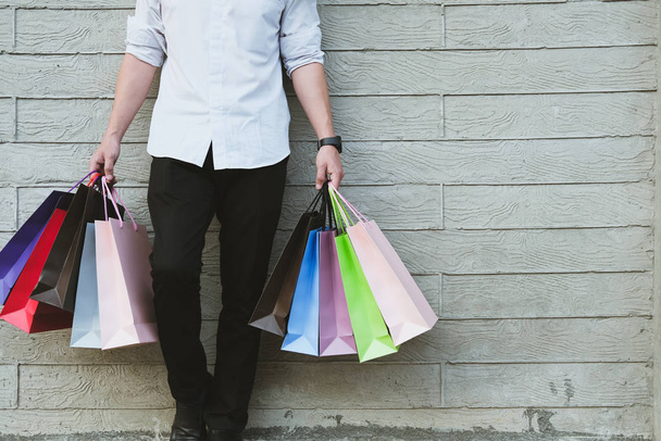 hombre sosteniendo colorido bolso de compras al aire libre. shopaholic macho stan
 - Foto, Imagen