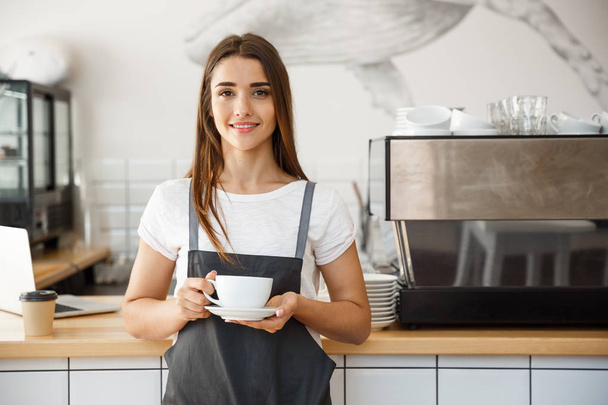 Coffee Business Concept - Caucasian female serving coffee while standing in coffee shop. Focus on female hands placing a cup of coffee. - Φωτογραφία, εικόνα