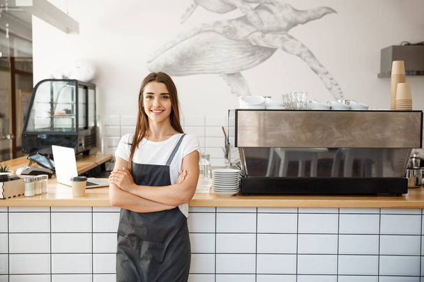 Coffee Business owner Concept - Portret młodej, atrakcyjnej, młodej, białej baristki w fartuchu uśmiechniętej do kamery w kafejce. - Zdjęcie, obraz