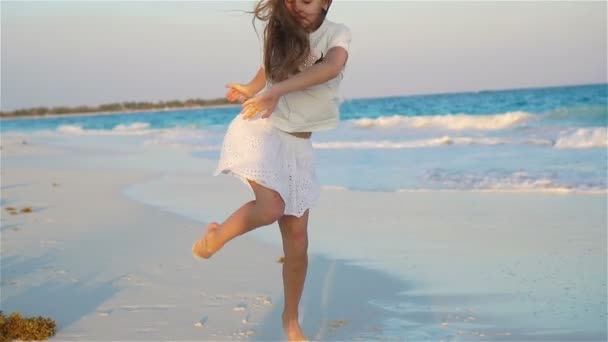 多くの楽しみを有するビーチでアクティブな少女。スポーティな子供の海岸の上で踊って - 映像、動画