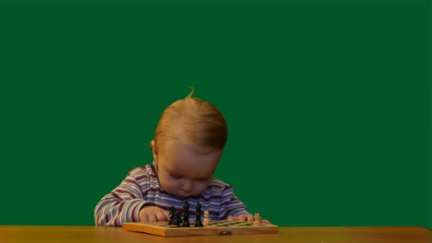 1 ετών baby κοντά στο τραπέζι με σκάκι πράσινο φόντο οθόνης - Πλάνα, βίντεο