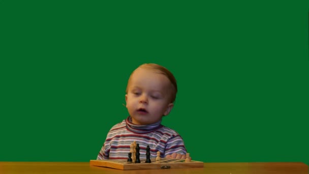 Bebé de 1 año cerca de la mesa con fondo de pantalla verde ajedrez
 - Metraje, vídeo