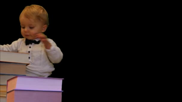 schattige 1 jaar oude baby met boeken stapel zwarte achtergrond verticale dolly schot - Video