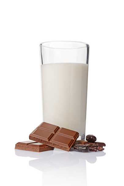 Close-up pieces of chocolate bar with cocoa beans and glass of milk - Фото, зображення