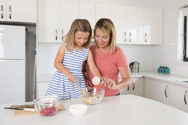 νεαρή μητέρα και γλυκιά μικρή κόρη του ψησίματος μαζί χαρούμενος στο σπίτι κουζίνα στην έννοια της οικογενειακής ζωής - Φωτογραφία, εικόνα