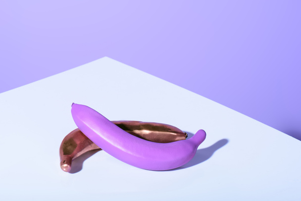 plátanos de plástico púrpura y dorado en la superficie violeta
 - Foto, imagen