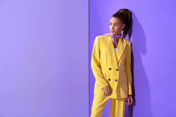 african american girl posing in yellow suit, on trendy ultra violet background - Photo, Image