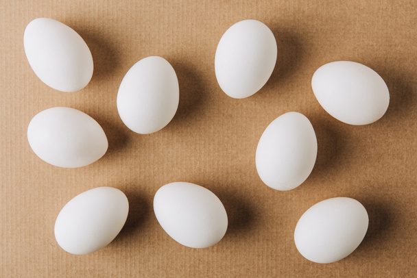 white eggs scattered on brown carton  - Photo, Image