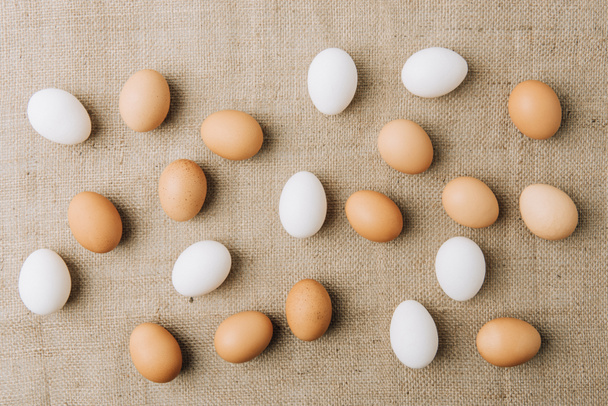 witte en bruine eieren scatterd op zak - Foto, afbeelding