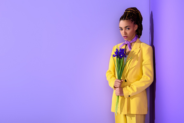 african american girl in yellow suit with irises, on trendy ultra violet background - Photo, Image