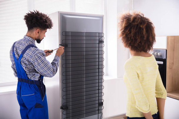 Woman Looking At Technician Repairing Refrigerator With Screwdriver In Kitchen - Fotoğraf, Görsel