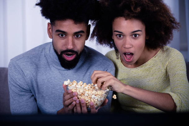 Shocked Couple Eating Popcorn While Watching Movie - 写真・画像