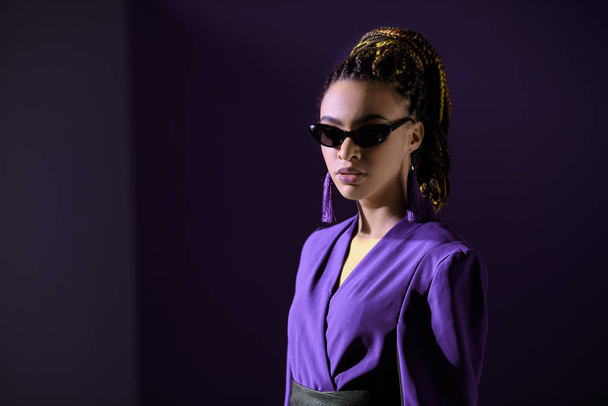 chica afroamericana elegante posando en chaqueta ultravioleta y gafas de sol
 - Foto, Imagen