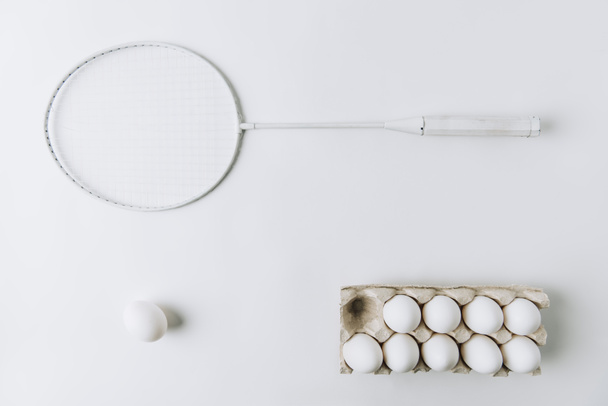 white egg on white background with another white eggs in carton and racket - Fotoğraf, Görsel
