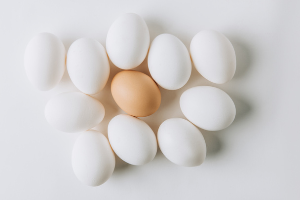 white eggs and one brown laying on white background - Photo, Image