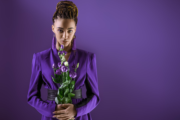 Elegáns mulatto modell jelentő lila virágokkal, elszigetelt ultra violet - Fotó, kép