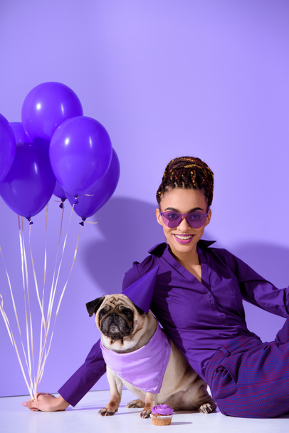 uśmiechający się african american girl pozowanie z fioletowe balony i mops, ultra violet trend  - Zdjęcie, obraz