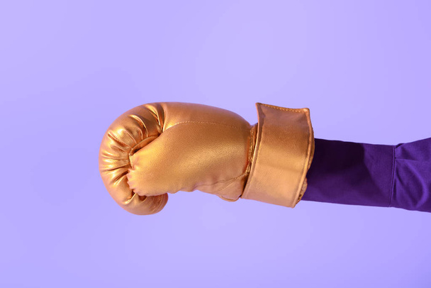 Ausgeschnittene Ansicht auf weibliche Hand in goldenem Boxhandschuh, isoliert auf Ultraviolett - Foto, Bild