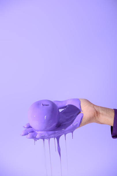 cropped view on female hand holding apple in purple paint, isolated on ultra violet - Photo, Image