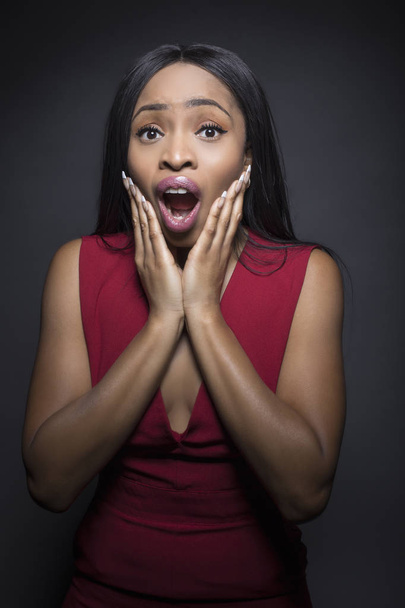 Black female model on a dark background with shocked and surprised expressions. - Fotoğraf, Görsel