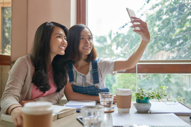 Досить Азіатська дівчинка, яка бере selfie в кафе - Фото, зображення