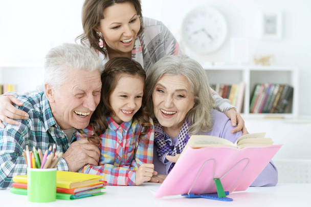 little cute girl with mother and grandparents  studying at  home - Photo, image