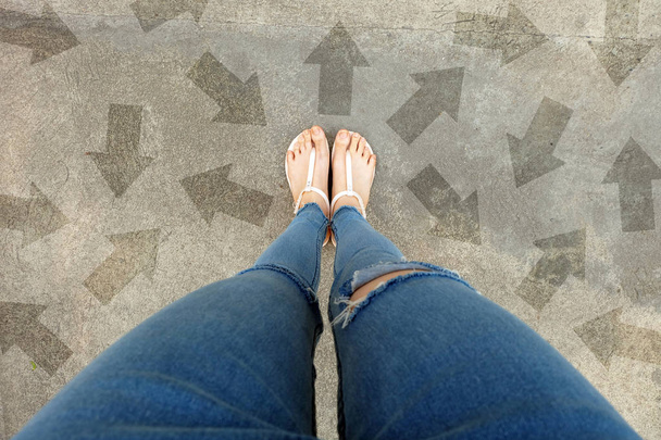 Selfie-Schuhe mit Richtungspfeilen. Frau Füße und Sandale stehen auf Betonfahrbahn Hintergrund ideal für jeden Einsatz. - Foto, Bild