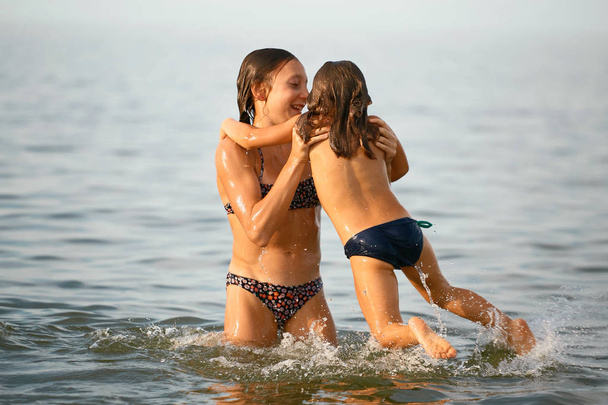 Meninas irmãs se divertir tomando banho no mar
 - Foto, Imagem