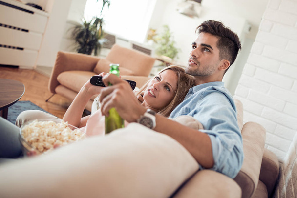 Young couple watching movie and eating popcorn - Fotó, kép