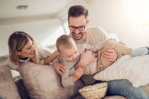 Tv-nézés és pattogatott kukoricát eszik a boldog fiatal család  - Fotó, kép