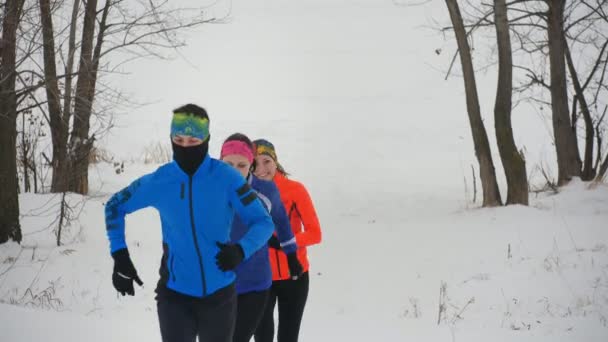 Grupo de três jovens atletas que correm tecnicamente na floresta de inverno
 - Filmagem, Vídeo