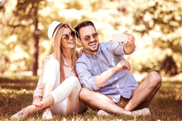 Счастливая молодая пара улыбается и делает селфи со смартфоном
 - Фото, изображение
