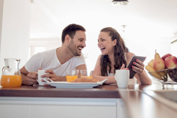 Jovem casal sentado no apartamento moderno e tomando café da manhã juntos
 - Foto, Imagem