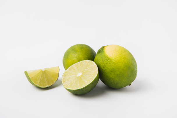whole and halved limes laying on white background    - Фото, изображение
