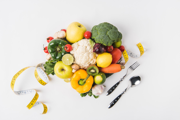 vegetables and fruits laying on white background with fork, spoon and measuring tape   - Photo, Image