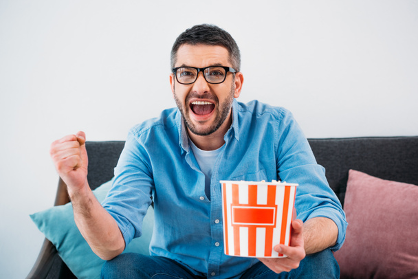 excited man with popcorn watching tv at home - Photo, Image