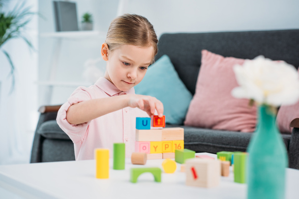 portrait of kid playing with colorful blocks in living room at home - Foto, Imagem