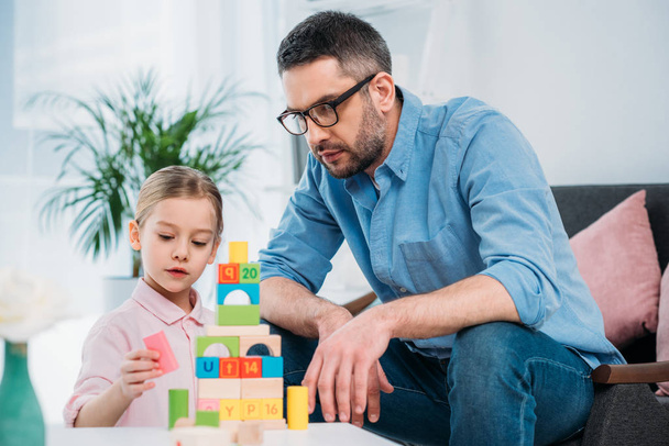 portrait of family building pyramid from colorful blocks at home - Fotografie, Obrázek
