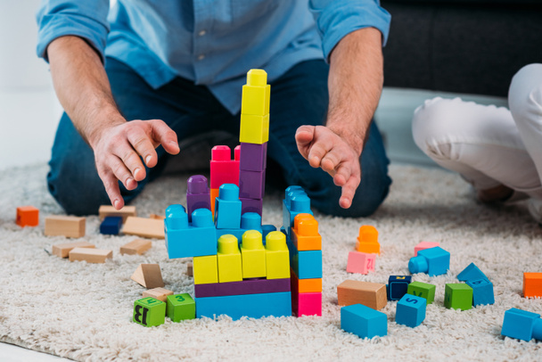 partial view of kid and father playing with colorful blocks together on floor at home - Photo, Image