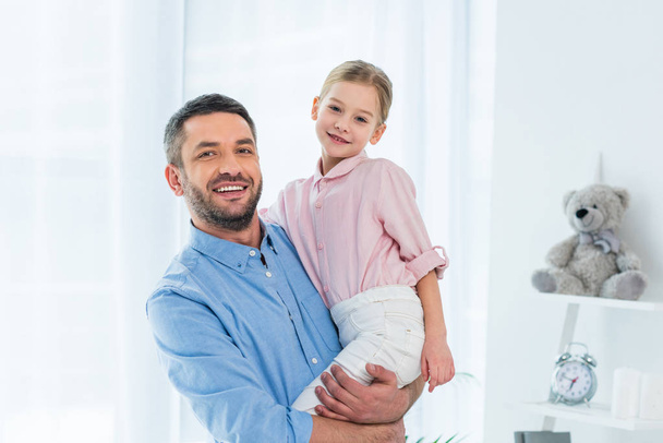 retrato de padre feliz sosteniendo a la pequeña hija en las manos en casa
 - Foto, imagen