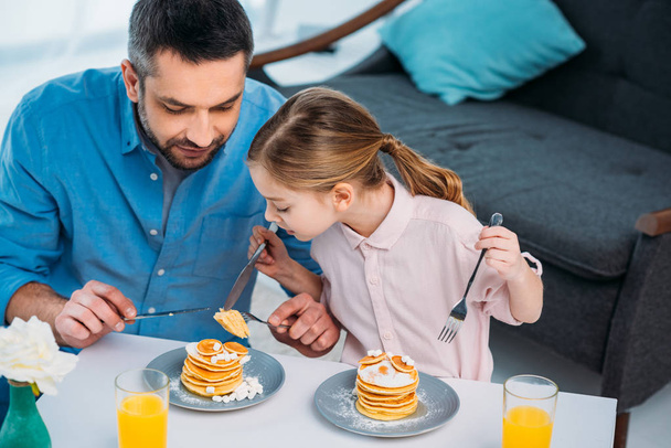 father and little daughter having breakfast at home - Foto, afbeelding