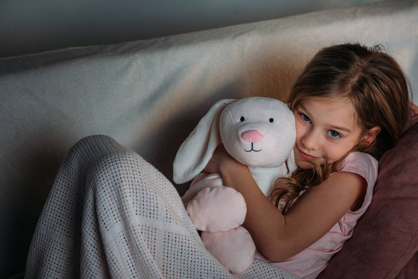 portrait of cute kid with toy resting on sofa - Foto, immagini