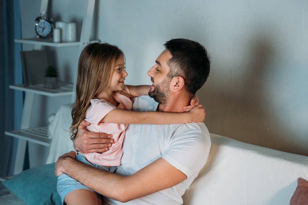 side view of smiling father and daughter looking at each other at home - Φωτογραφία, εικόνα