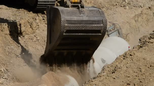 Excavadora de construcción enterrando una zanja con tuberías
 - Metraje, vídeo