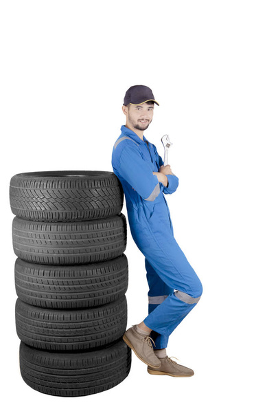 Handsome mechanic posing with stack of tires - Foto, afbeelding